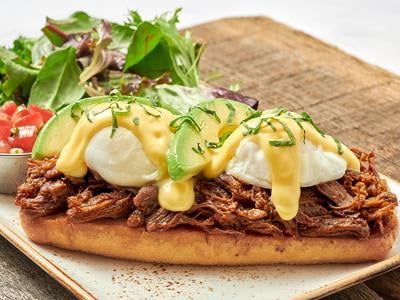 Two cage-free poached eggs atop toasted ciabatta with seasoned braised beef Barbacoa, hollandaise, sliced avocado, scallions and a side of housemade pico de gallo.