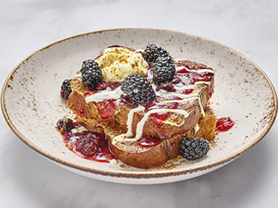 Thick-cut, custard-dipped challah bread griddled and topped with lemon cream, fresh blackberries, mixed berry compote, creme anglaise and spiced gingerbread cookie crumbles. Lightly dusted with powdered cinnamon sugar.