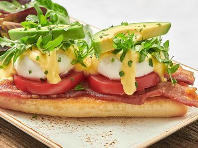 Two poached cage-free eggs atop toasted ciabatta piled high with bacon, vine-ripened tomato, avocado and lemon-dressed arugula and covered with hollandaise. Served with lemon-dressed organic mixed greens.
