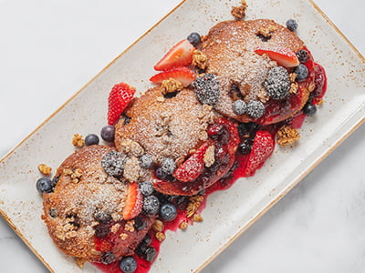 Three house-baked, butter-griddled blueberry and cinnamon streusel muffin tops, topped with warm mixed berry compote, fresh blueberries, strawberries and blackberries, housemade granola and powdered cinnamon sugar.