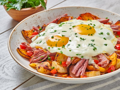 Savory hand-pulled corned beef, freshly seasoned potatoes, house-roasted sweet potatoes, onions and red bell peppers topped with two cage-free eggs cooked any style, Parmesan cream sauce and fresh herbs.