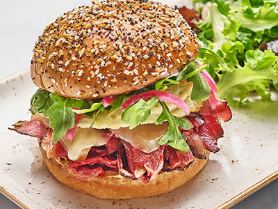 Inspired by a New York deli classic - shaved pastrami, Gruyere cheese and house-roasted onions with an over-easy cage-free egg, house-pickled red onions, arugula, mayo and Dijon mustard on a griddled everything-seasoned brioche bun. Served with lemon-dressed organic mixed greens.