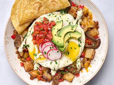Thinly sliced carne asada, crumbled chorizo and diced red bell peppers in a potato hash topped with two cage-free eggs any style, Cheddar and Monterey Jack, housemade pico de gallo, fresh avocado, shaved radish, cilantro and jalapeno crema. Served with two warm wheat-corn tortillas.