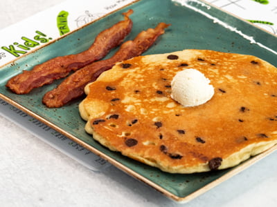 One of our humongous multigrain pancakes loaded with chocolate chips and topped with creamy butter. Served with your choice of bacon or sausage.