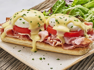 Two poached cage-free eggs atop toasted ciabatta piled high with smoked ham and vine-ripened tomato and covered with hollandaise. Served with lemon-dressed organic mixed greens.