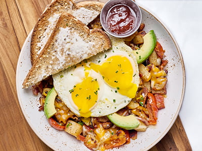 Two cage-free eggs any style atop fresh, seasoned potatoes, bacon, avocado, house-roasted onions and tomatoes, Cheddar and Monterey Jack. Served with whole grain artisan toast.