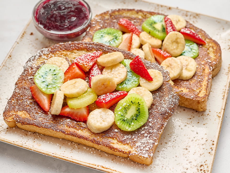 Thick-cut brioche bread with wheat germ and powdered cinnamon sugar, covered with fresh banana, kiwi and seasonal berries.