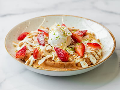 Our light and airy Belgian waffle topped with Key Lime Pie filling, spiced shortbread cookie crumble, whipped cream, toasted coconut chips, fresh strawberries, lime zest and cinnamon powdered sugar.