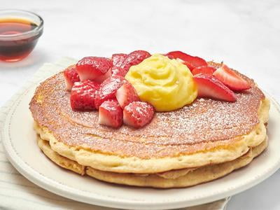 A "mid-stack" of two whipped ricotta multigrain pancakes topped with seasonal berries, creamy lemon curd and powdered cinnamon sugar.