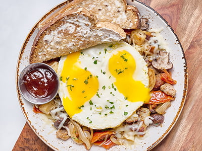 Two cage-free eggs any style atop fresh, seasoned potatoes, Italian sausage, house-roasted Crimini mushrooms, onions and tomatoes with melted Parmesan, Mozzarella and fresh herbs. Served with whole grain artisan toast.