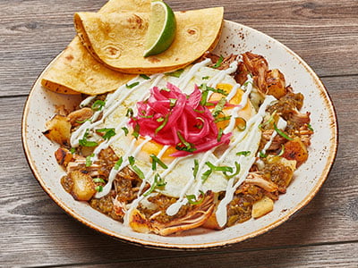Hand-shredded pork shoulder tossed with freshly seasoned potatoes, Monterey Jack, fire-roasted green chile sauce and lime crema. Topped with two cage-free eggs cooked any style, house-pickled red onions and cilantro. Served with warm wheat-corn tortillas and freshly cut lime. 