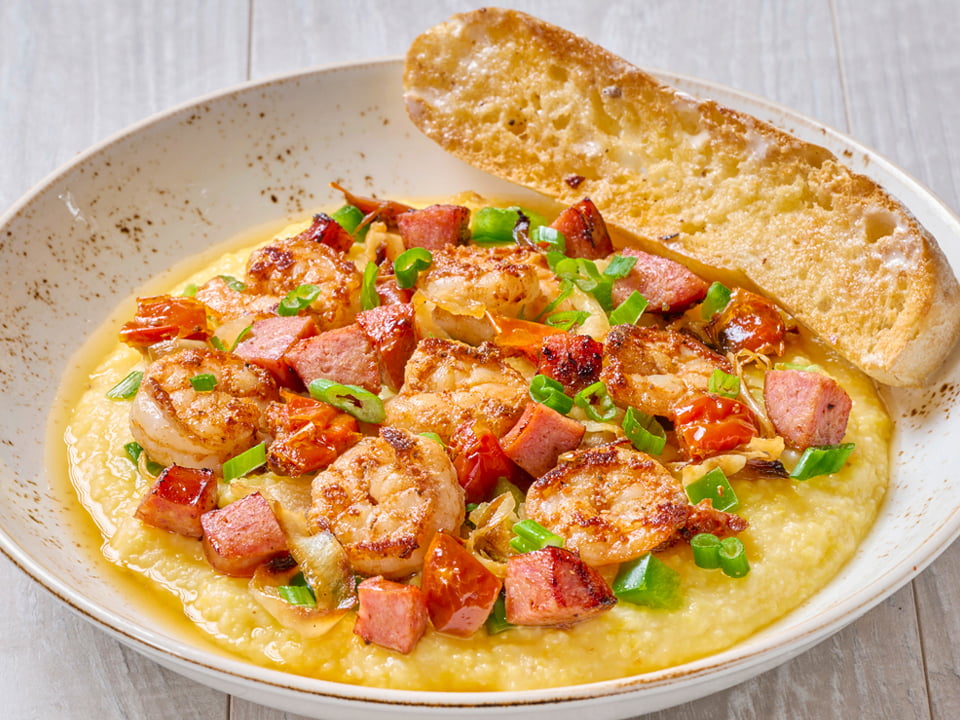 Sauteed Cajun shrimp and andouille sausage cooked Lowcountry-style with chicken stock, house-roasted tomatoes, onions, green bell peppers and scallions atop Bob's Red Mill Cheddar Parmesan cheese grits. Served with artisan ciabatta toast.