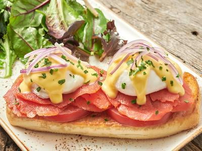 Two poached cage-free eggs atop toasted ciabatta piled high with Wild Alaska Smoked Sockeye Salmon, red onion and vine-ripened tomato and covered with hollandaise. Served with lemon-dressed organic mixed greens.