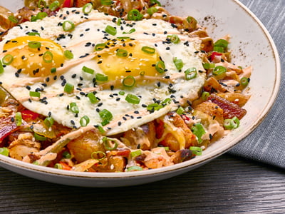 Shaved seared pork tossed with freshly seasoned potatoes, diced red bell peppers, kimchi, Cheddar and Monterey Jack. Topped with two cage-free eggs cooked any style, scallions, sesame seeds and gochujang aioli.