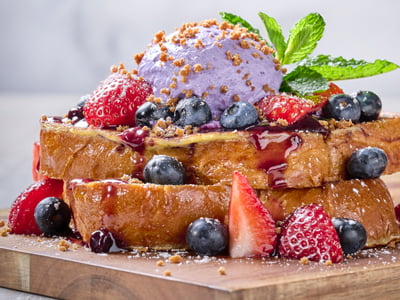 Thick-cut, custard-dipped challah bread griddled and topped with fresh strawberries and blueberries, warm mixed berry compote, lavender whipped cream, spiced gingerbread cookie crumbles and mint. Lightly dusted with powdered cinnamon sugar.