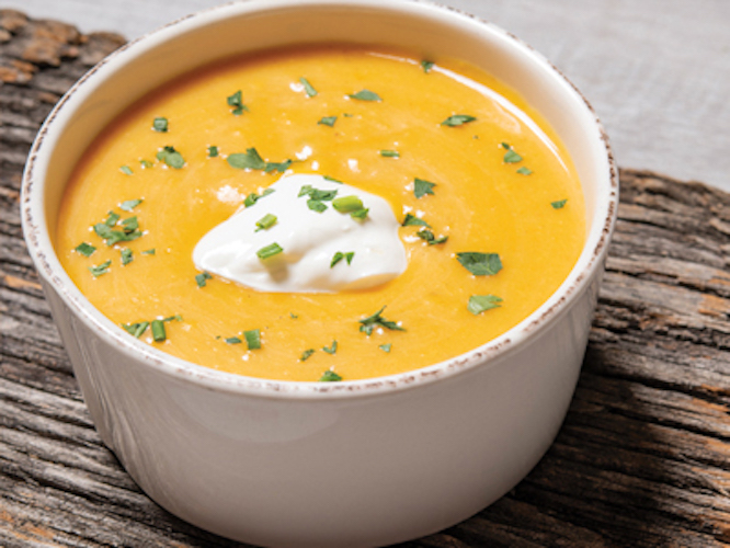 A bowl of butternut bisque topped with cream and chives.