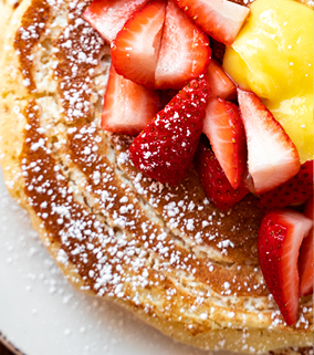 A plate of lemon ricotta pancakes and strawberries.